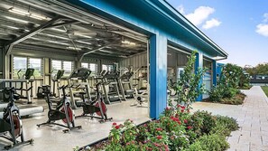 A covered outdoor gym area with stationary bikes and treadmills.