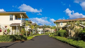 A residential street with houses, a clear sky, and lush greenery.