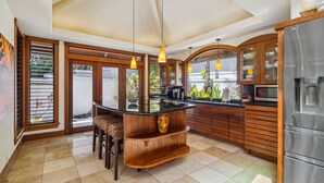 Eine moderne Küche mit Kochinsel, Holzschränken und einem Edelstahl-Kühlschrank.