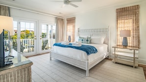 A bedroom with a bed, a ceiling fan, a nightstand, and a view of the outdoors through a sliding glass door.