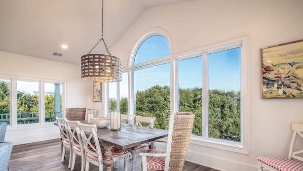 A dining area with a wooden table, white chairs, and a hanging light fixture.
