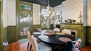 Ein Esszimmer mit dunklem Holztisch, grünen Wänden und einer Kronleuchter.