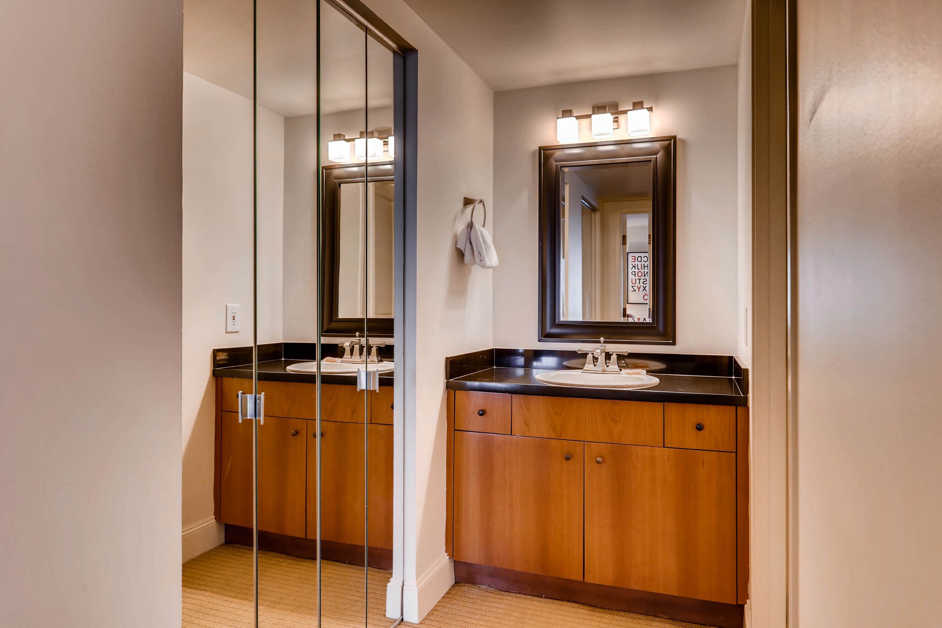 Une salle de bain avec un meuble-lavabo double, des armoires en bois, un grand miroir et un porte-serviettes.