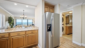 Une cuisine moderne avec des meubles en bois, un réfrigérateur en acier inoxydable, un plan de travail en granit et une vue sur l’extérieur.
