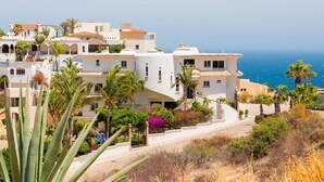 Un quartier résidentiel en bord de mer, avec des bâtiments blancs, des palmiers et une vue dégagée sur la mer.