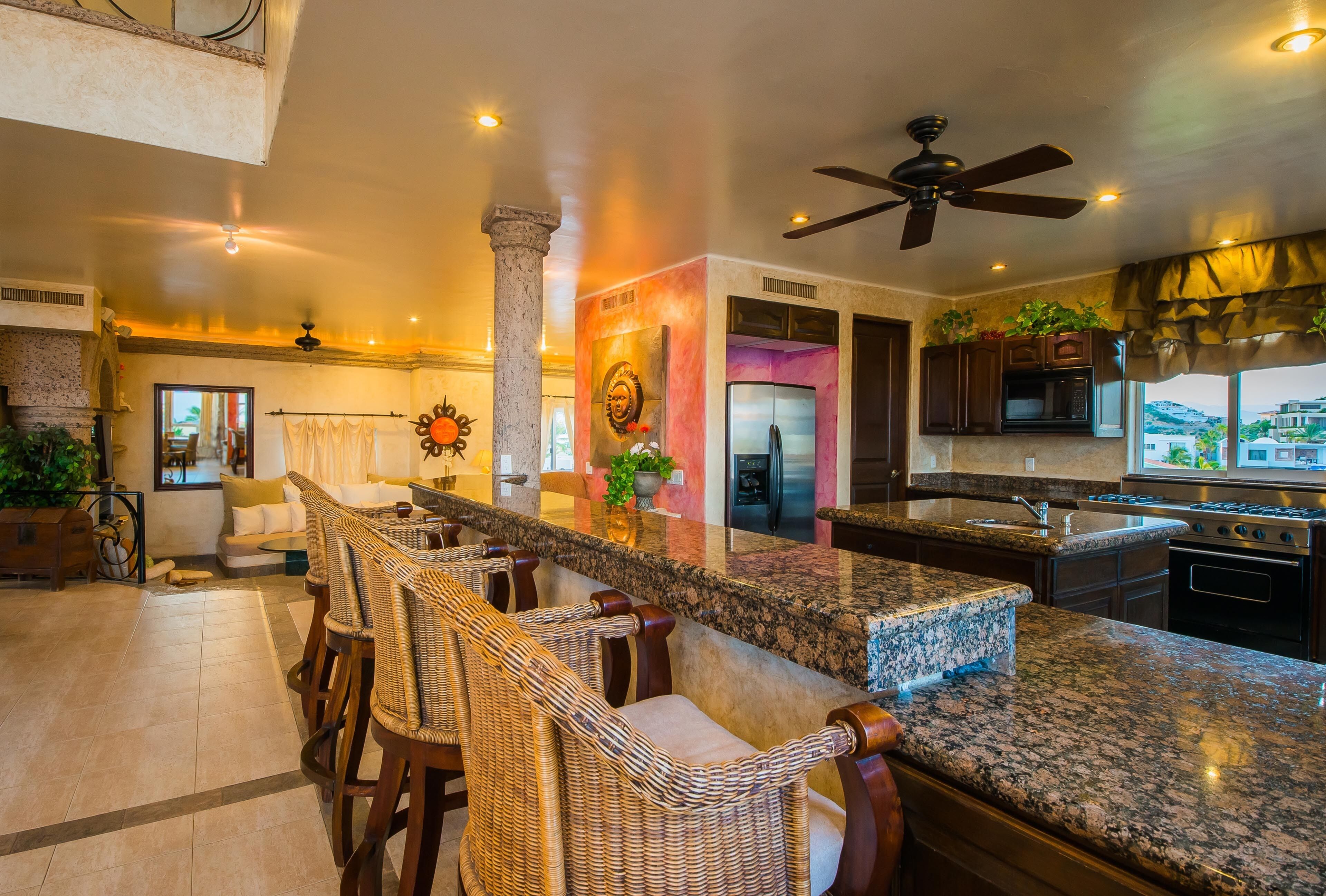A spacious kitchen with a large island, bar stools, and a view of the city.