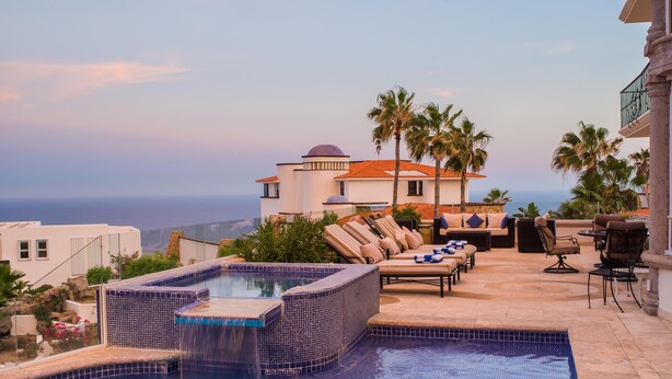 Un espace piscine extérieur luxueux, doté d’un jacuzzi, de chaises longues et offrant une vue sur l’océan.