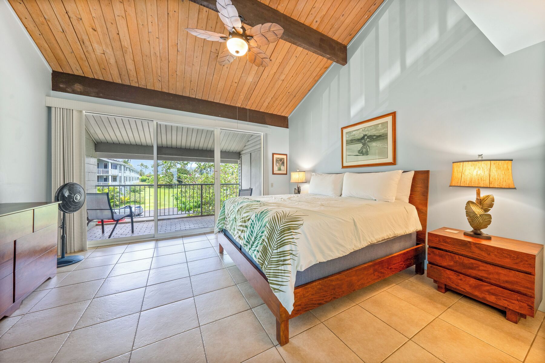 A bedroom with a bed, a nightstand, a chair, a fan, and a ceiling fan.