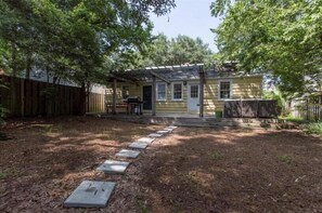 A yellow house with a covered porch, a wooden fence, and a stone pathway leading to the front.