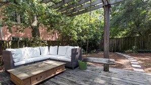 A wooden deck with a white sectional sofa and a bench.