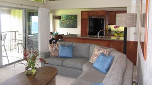 A modern living room with a grey sectional sofa, a wooden coffee table, and a potted plant.