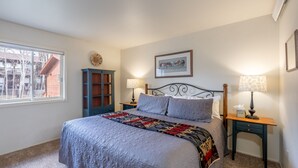 Een slaapkamer met een groot bed, twee nachtkastjes, een raam en een aan de muur hangend schilderij.