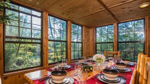 A dining table set for four with a forest view through large windows. - Family Cabin on 6 Acres w/ Lake Access & Hot Tub! (Springfield)