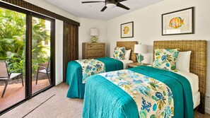 Une chambre d’hôtel avec deux lits, une grande fenêtre avec des rideaux, un ventilateur de plafond et des œuvres d’art représentant des poissons, encadrées et accrochées au mur.