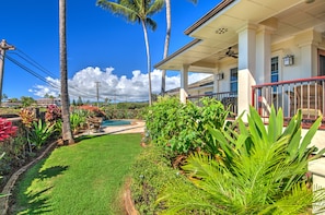 A house with a swimming pool, surrounded by lush greenery and palm trees.