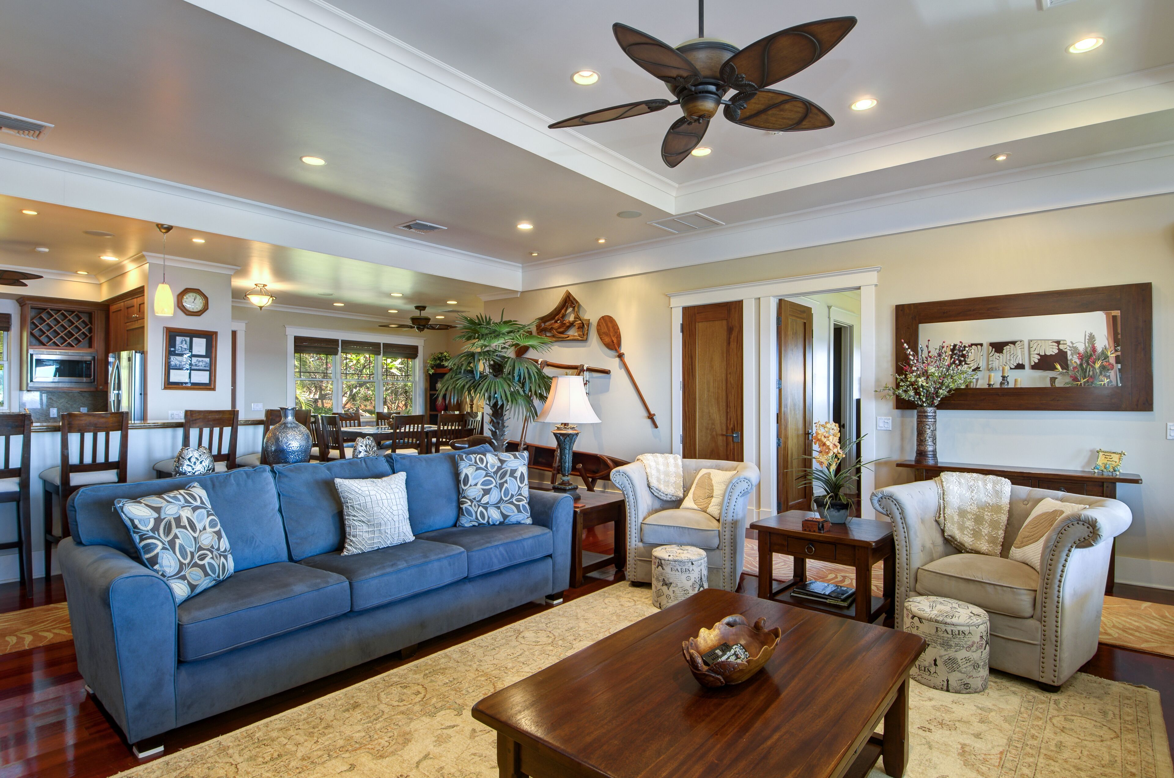 A spacious living room with a blue sofa, a wooden coffee table, and a ceiling fan.