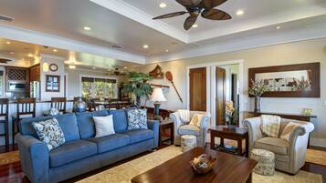 A spacious living room with a blue sofa, a wooden coffee table, and a ceiling fan.