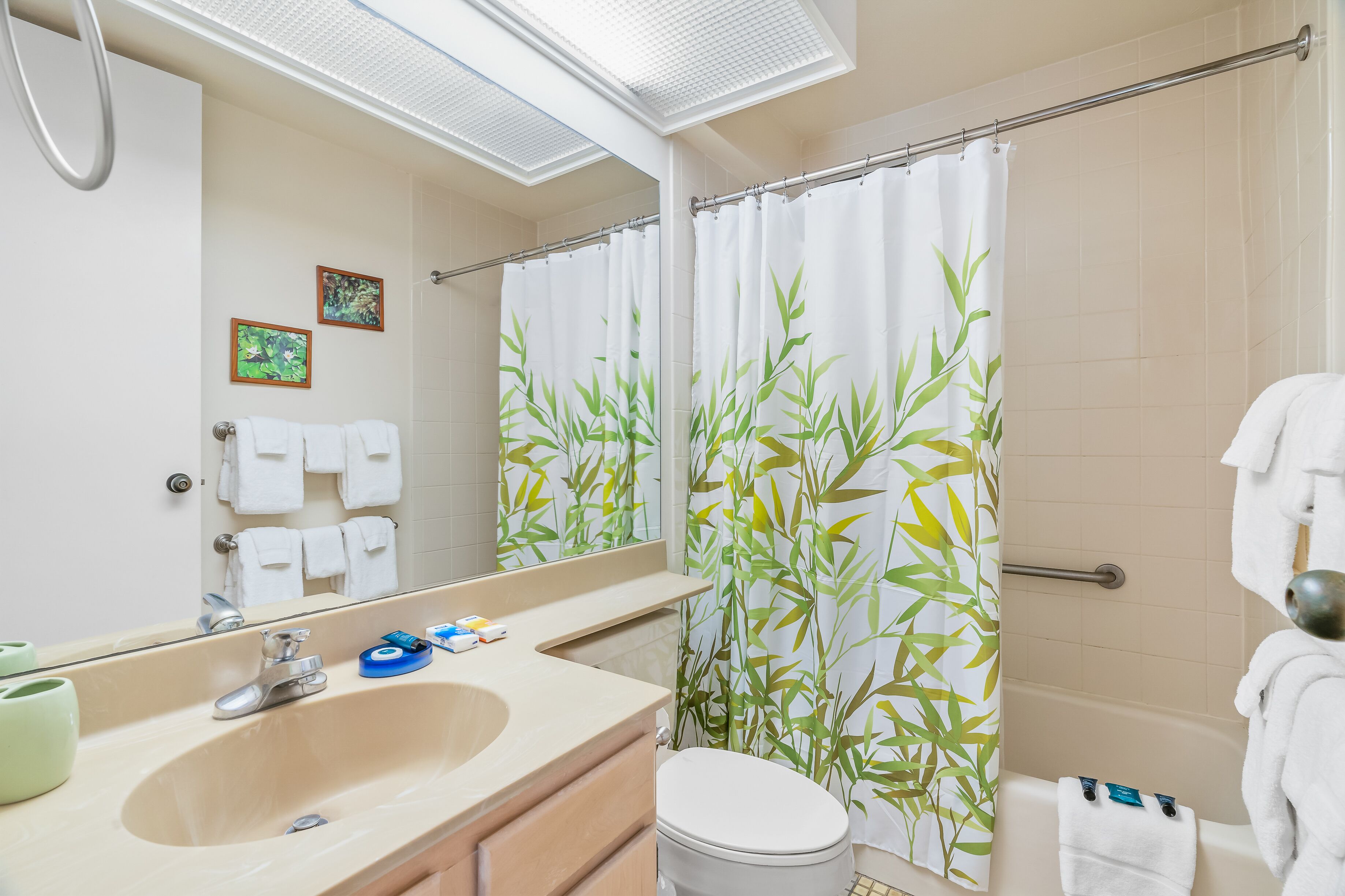 Un baño con lavamanos, espejo, inodoro y cortina de ducha.