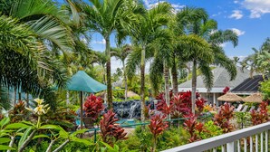 Un exuberante resort tropical con una cascada, palmeras y un área de piscina.