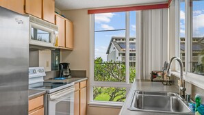 Una cocina moderna con electrodomésticos de acero inoxidable, un ventanal con vistas a un barrio residencial y un horno empotrado.