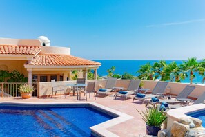 Un espace piscine avec des chaises longues et vue sur l’océan.