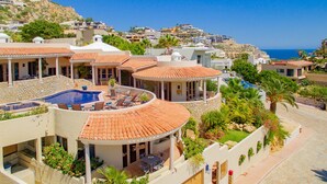 A coastal resort with multiple buildings, a swimming pool, and a view of the sea.