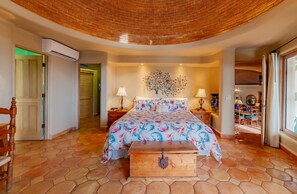 Une chambre à coucher comprenant un lit, une commode, une table de chevet et un climatiseur fixé au mur.