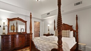 A four-poster bed with a wooden headboard, a dresser with a mirror, and a small stool. - Garden Level Steps from Shops and Restaurants by Lucky Savannah (Savannah)