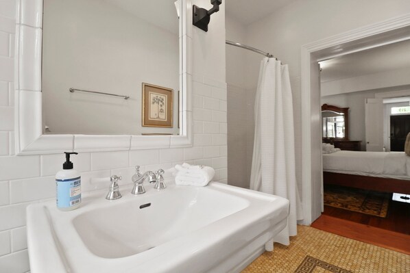 A bathroom with a white sink, a framed picture on the wall, and a shower curtain.
