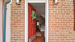 A red door with a wreath, a white couch, and a wooden floor. - Garden Level Steps from Shops and Restaurants by Lucky Savannah (Savannah)