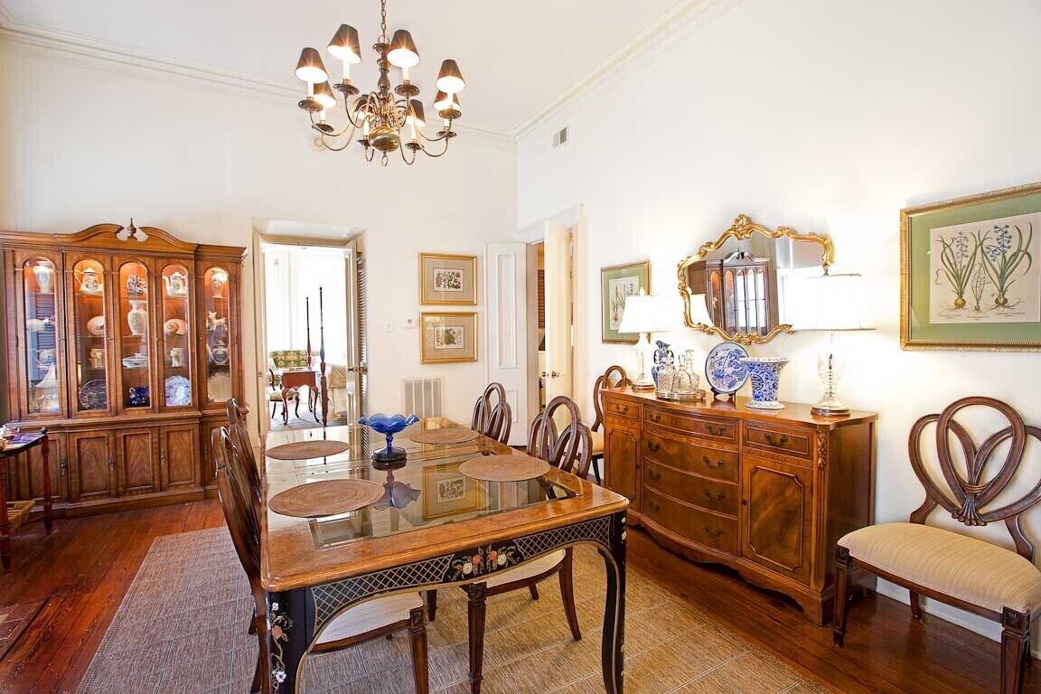 A traditional dining room with a wooden table, chairs, a chandelier, and a cabinet with glass doors.