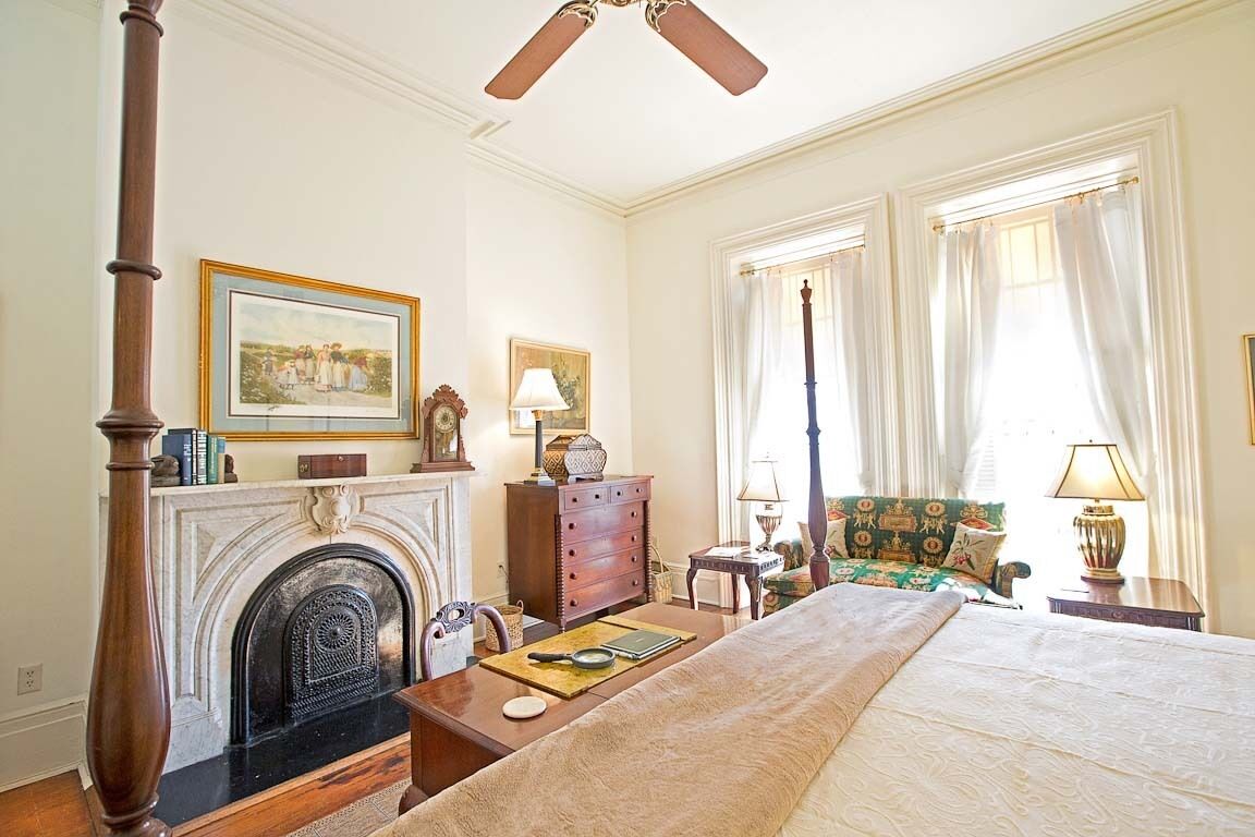 A hotel room with a fireplace, a bed, a chair, and a table.