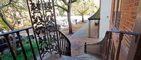 A staircase with a metal railing leading to a covered area with a brick wall.