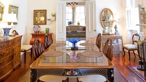 Une salle à manger avec une table à plateau de verre, des chaises en bois et une vue sur le salon grâce à une porte ouverte.