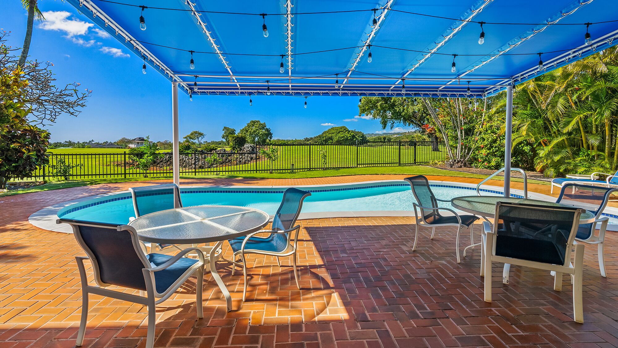 Un espacio al aire libre techado con piscina, sillones de descanso y una mesa.