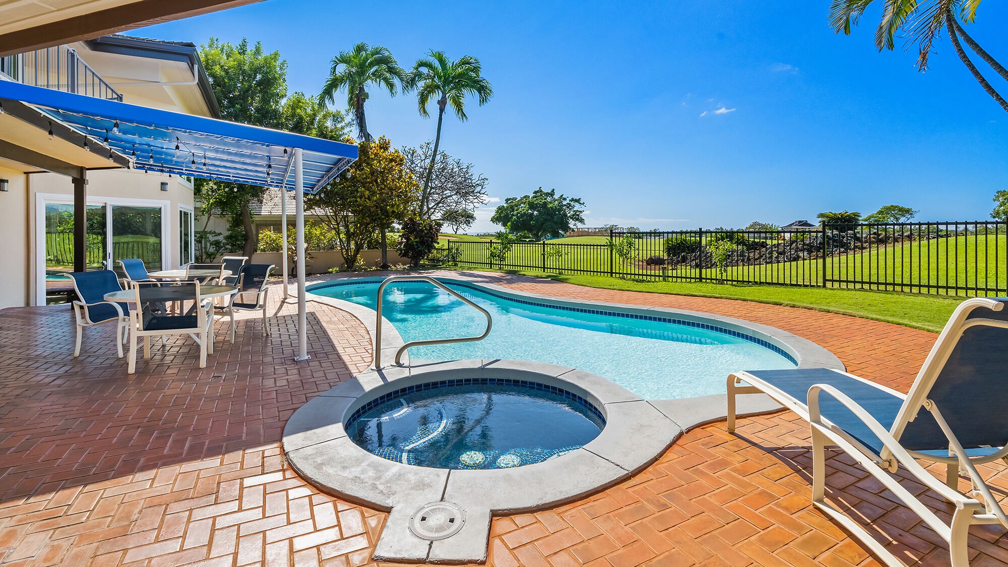 A swimming pool with a hot tub, outdoor seating, and a covered patio area.