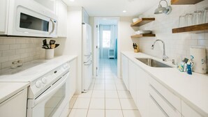 Una cocina moderna con armarios blancos, microondas, estufa y pileta.