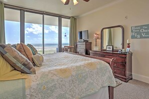 Un dormitorio con una cama grande, un aparador, televisión y un balcón con vista al cielo.