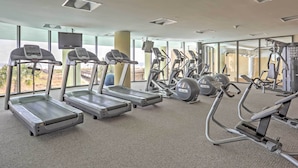 Ein Fitnessraum mit Laufbändern, Crosstrainern und Gewichten.