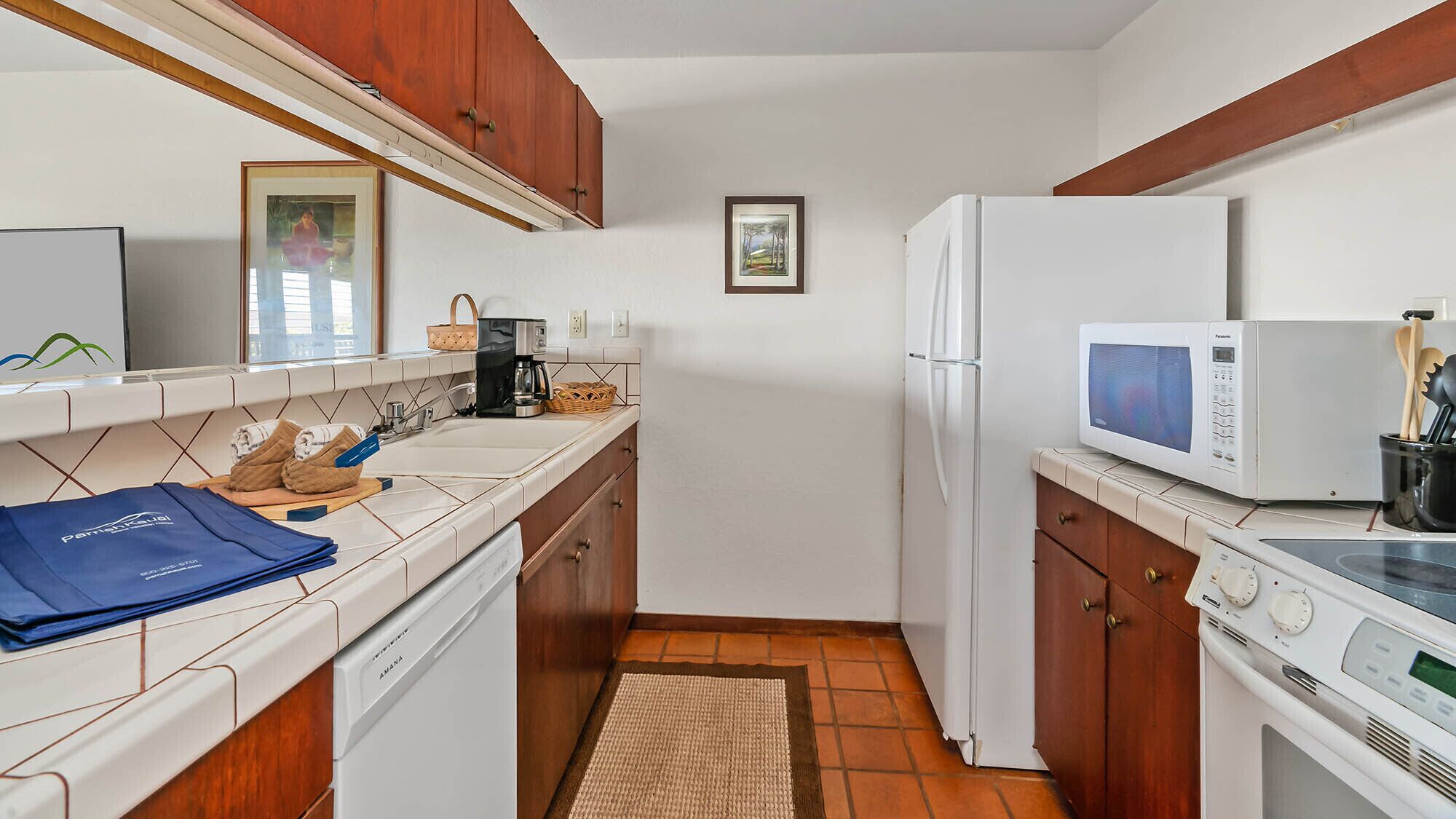Una cocina compacta con electrodomésticos blancos, armarios de madera y salpicadero de azulejos.