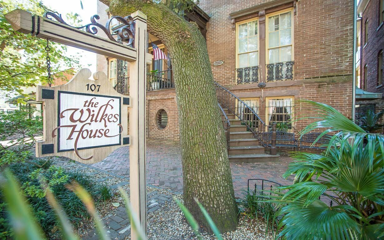 Señal de 'The Wilkes House' en el número 107, con un edificio de ladrillo y una escalera que lleva a un nivel superior.