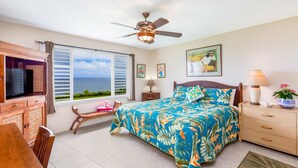 A bedroom with a bed, a TV, a desk, and a window with a view of the ocean. - Expansive Ocean Views from Ali'i Kai 5103 (Princeville)