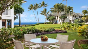 Un resort tropical con una mesa redonda y sillas, un frutero y vista al océano.
