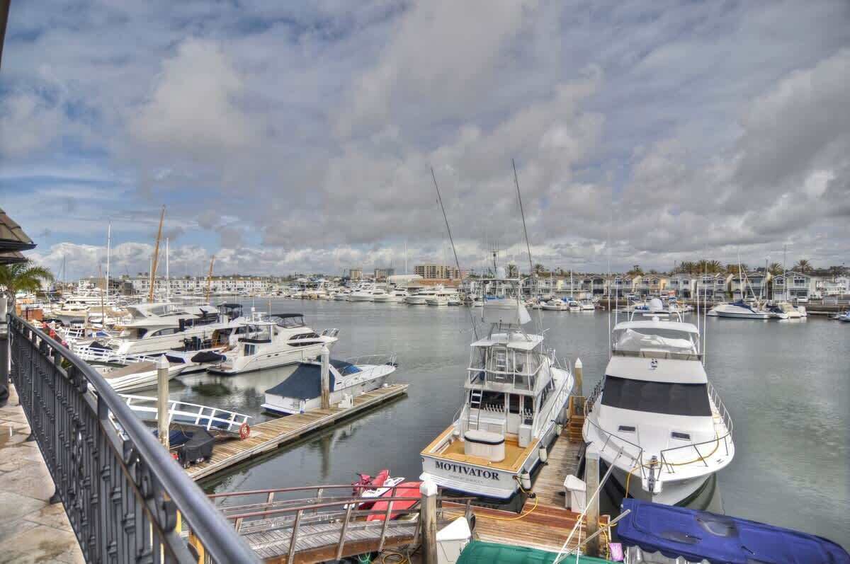 Eine Marina mit mehreren angedockten Booten, darunter eine auffällige Yacht namens 'MOTIVATOR', und einer Stadtlandschaft im Hintergrund.
