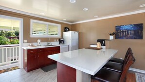 A modern kitchen with a white countertop, dark wooden cabinets, a refrigerator, and a painting on the wall. - Nalo Studio A By Parrish Kauai - local vibe & walk to Poipu Beach (Koloa)