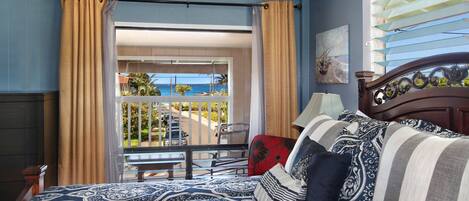 A hotel room with a balcony overlooking a beach and ocean.