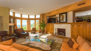 Ein geräumiges Wohnzimmer mit großem Fenster, Kamin und Fernseher.