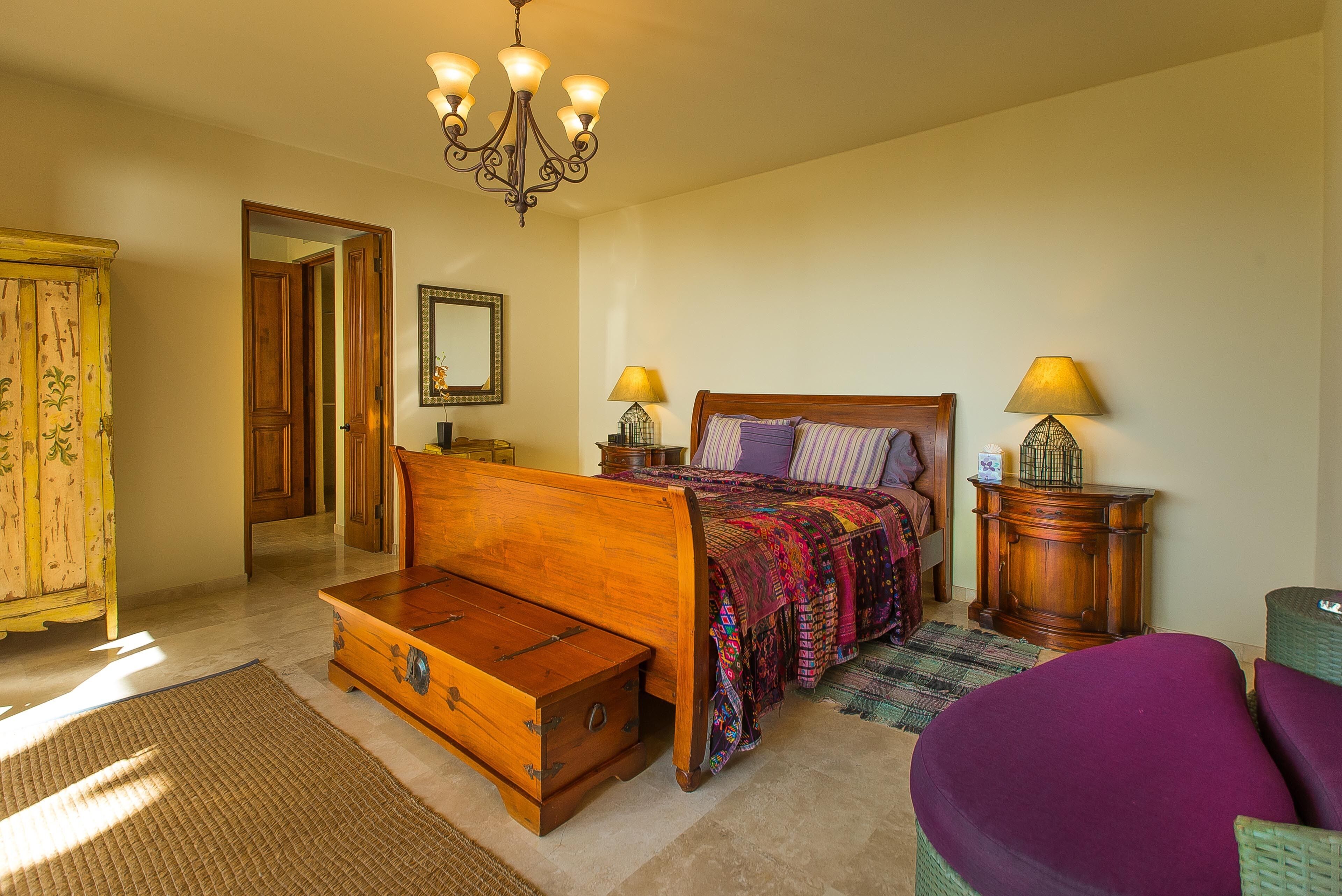 Een slaapkamer met een houten bed, twee bedlampen, een dressoir en een ladekast.