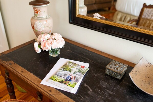 Una mesa de madera con un jarrón de flores, una revista y una caja decorativa.