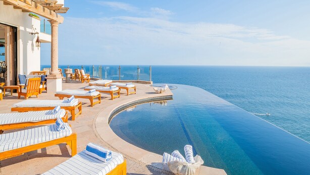 Ein Poolbereich mit Liegestühlen und Blick auf den Ozean.